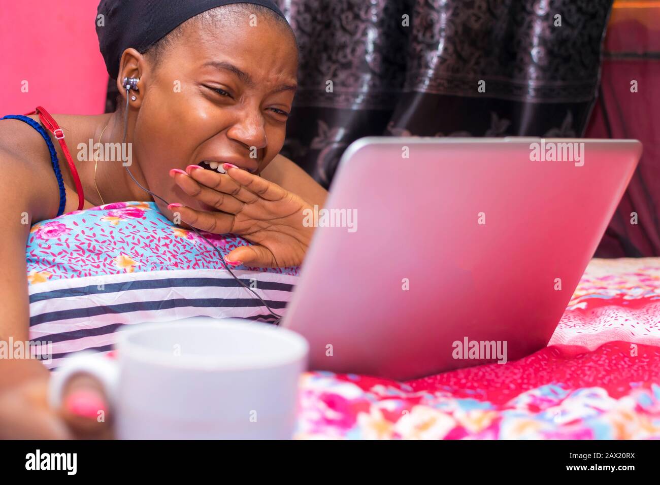 jolie dame africaine à la maison seule dans sa chambre, regarder un film sur son ordinateur portable, bâillonne Banque D'Images