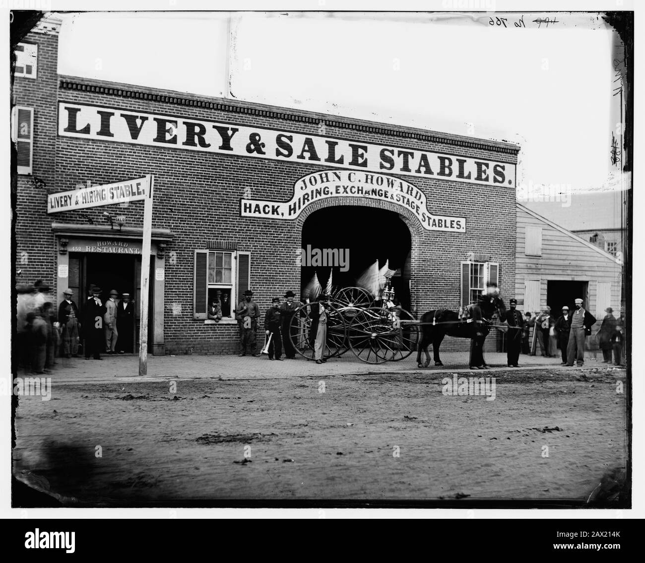 1865, WASHINGTON, États-Unis : l'écurie de John C. Howard sur G Street entre le 6 et le 7 (où John H. Surratt a gardé les chevaux avant de quitter la ville le 1er avril 1865). John H. SURRATT Jr ( 1844 - 1916 ), fils DE MARY SURRATT ( 1820 - 1865 ) la femme a réputé un des conspirateurs américains Abraham LINCOLN ( 1809 - 1865 ) et condamné à mort par pendaison . - Presidente della Repubblica - Stati Uniti - USA - ritratto - portrait - Abramo - processo di cospirazione - people - genta - carro - carrozza - calesse - cavallo - cheval - écuries - officina - drapeau - bandiera -- Archivio GBB Banque D'Images
