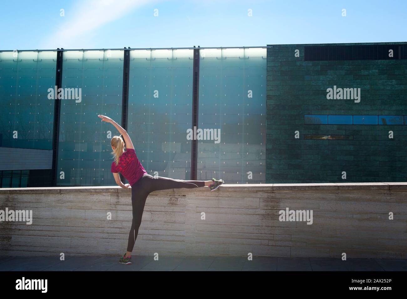 Jeune fille sportive en haut et leggings faisant des exercices de striching yoga pose. Jolie femme tenant les mains et les jambes, tentant tout le corps, modernoutdoor à Banque D'Images