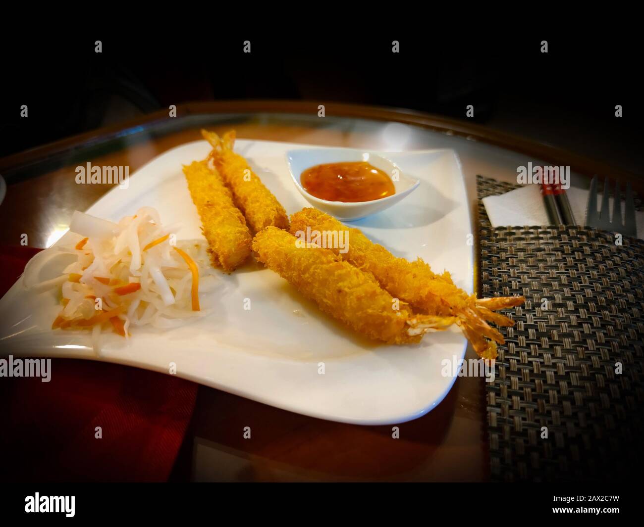 Crevettes panées fritures asiatiques dans le restaurant vietnamien. À côté, il y a des baguettes alimentaires et de la sauce aigre-douce. Banque D'Images