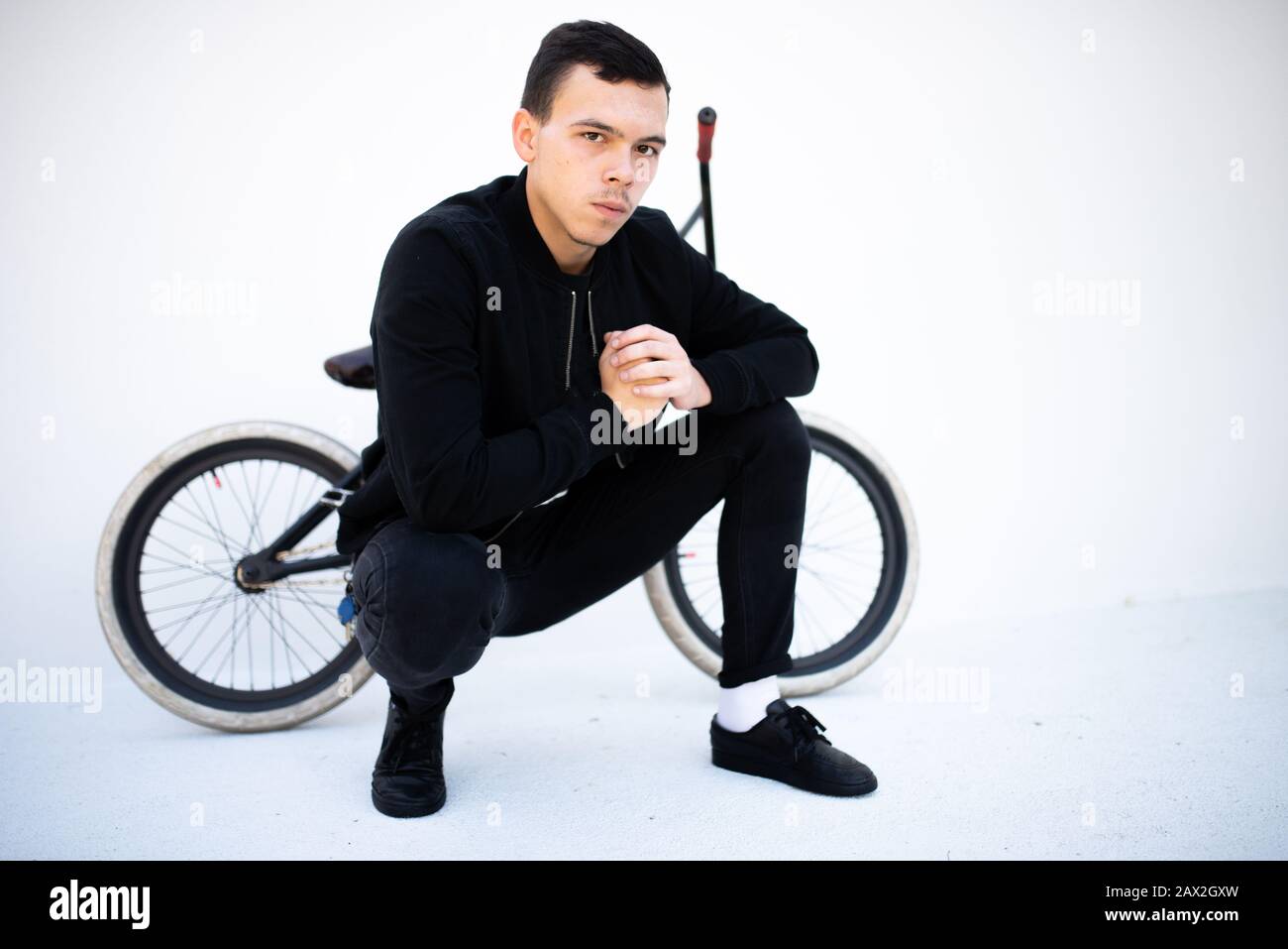 Un gars est assis à côté d'un vélo BMX. Banque D'Images