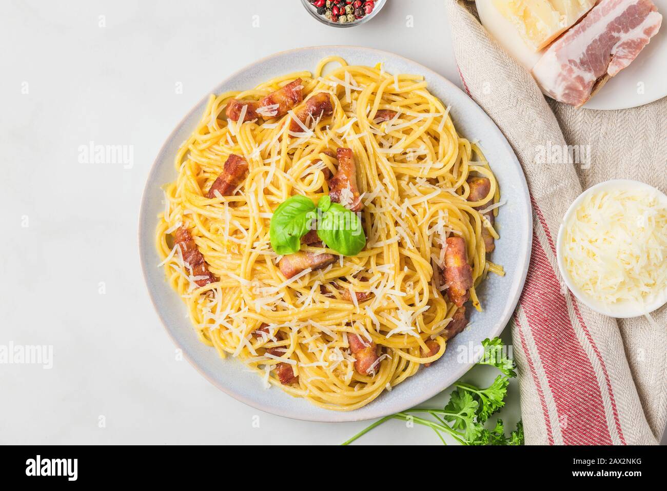 Pâtes italiennes carbonara faites de spaghetti, bacon, parmesan et basilic dans une assiette sur table en marbre blanc. Vue sur le dessus Banque D'Images