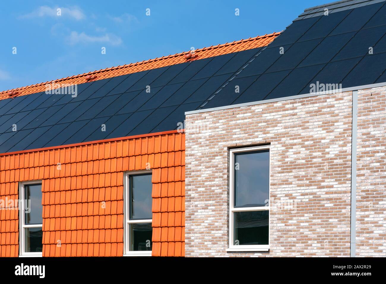 Capteurs solaires sur un toit d'une façade en brique revêtue et tuiles de toit bâtiment revêtus de façade. Espace pour le texte. Banque D'Images