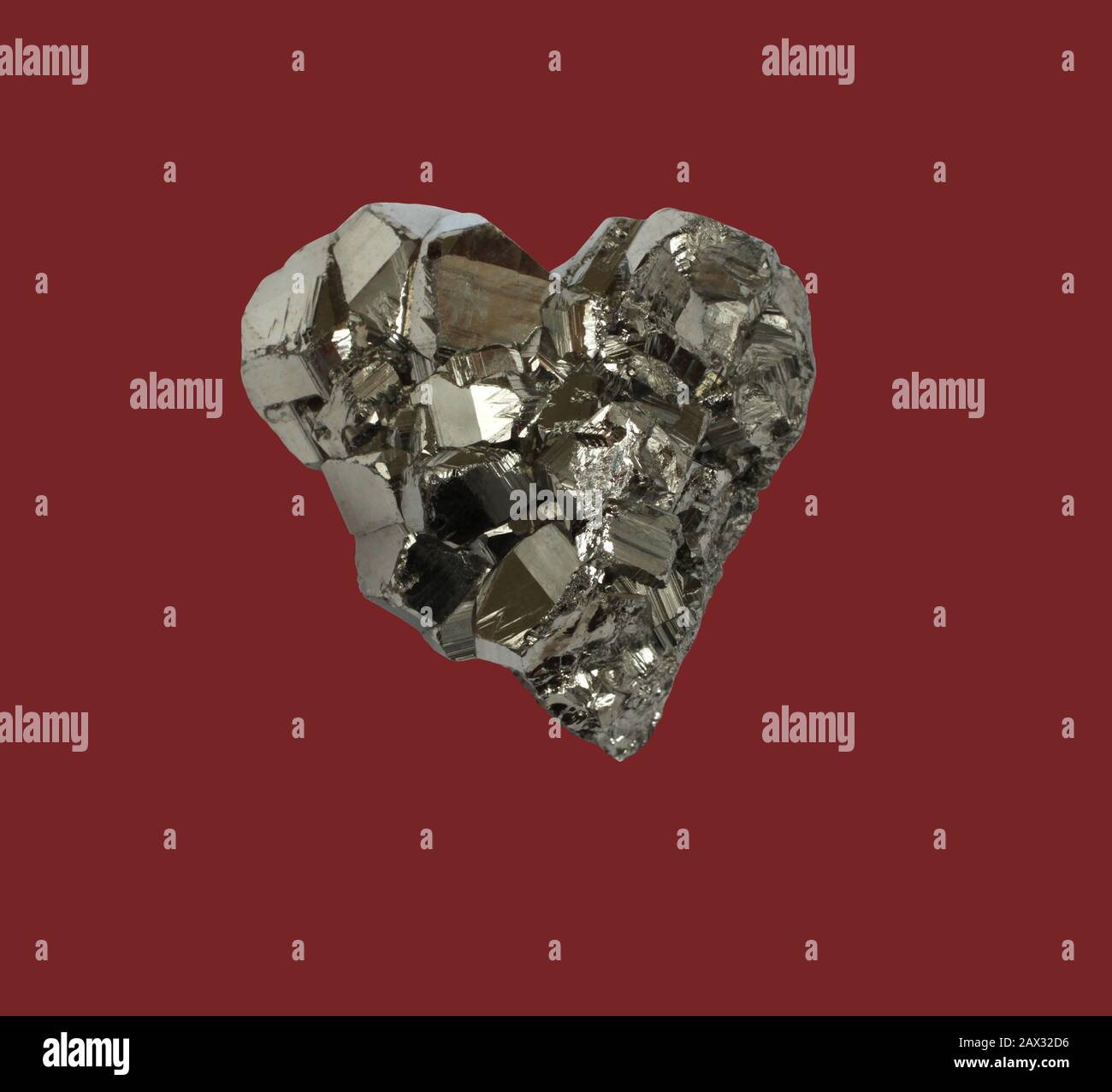 Pyrite minérale en forme de coeur sur fond rouge foncé Banque D'Images