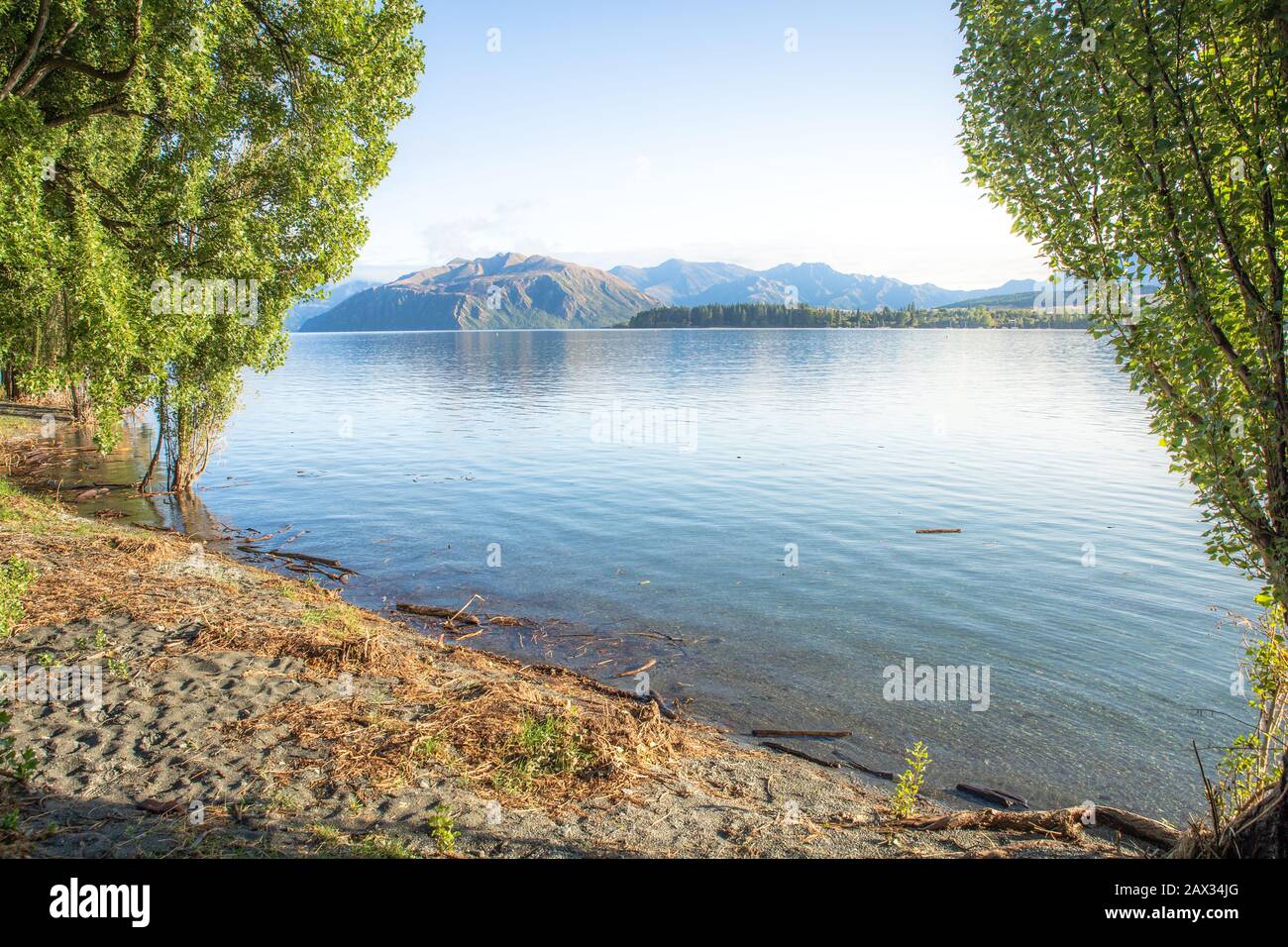Lever du soleil du lac tôt le matin avec lumière dorée. Ciel bleu et eau. Lac Wanaka Nouvelle-Zélande, destination De voyage Populaire. Banque D'Images