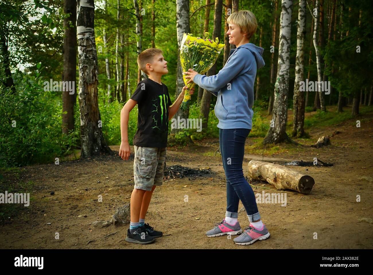 Son donne des fleurs à sa mère dans la nature sur le lac Banque D'Images