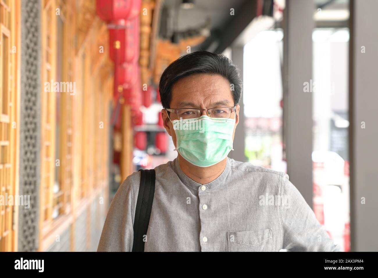 Portrait de l'homme chinois asiatique portant un masque chirurgical. Protection contre le virus ou la brume en extérieur. Banque D'Images