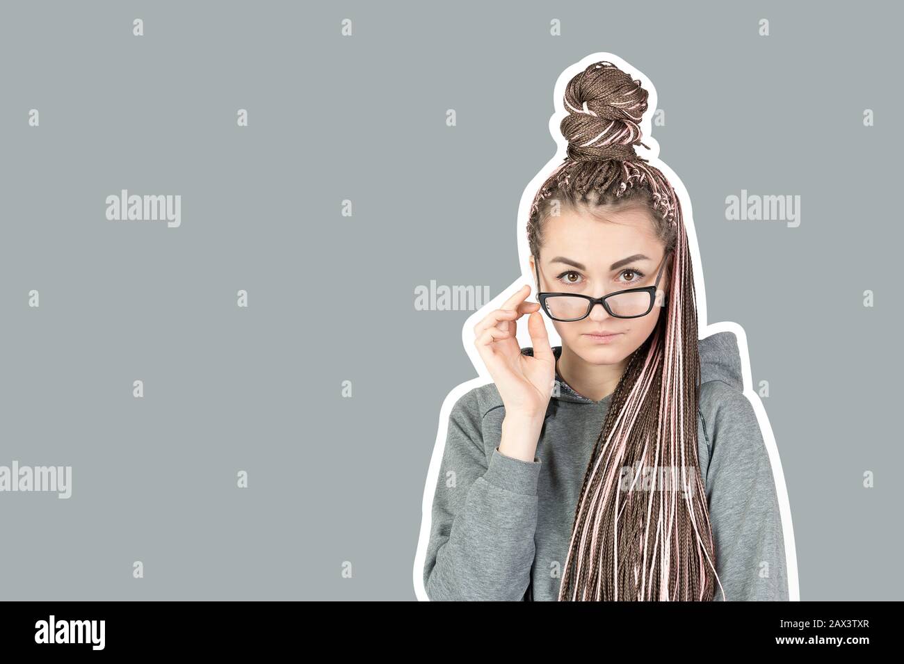 Belle fille stricte avec des piquets roses zizi abaissé ses verres et regarde derrière eux à l'appareil photo sur un fond gris avec un trait ou un cadre. Con Banque D'Images