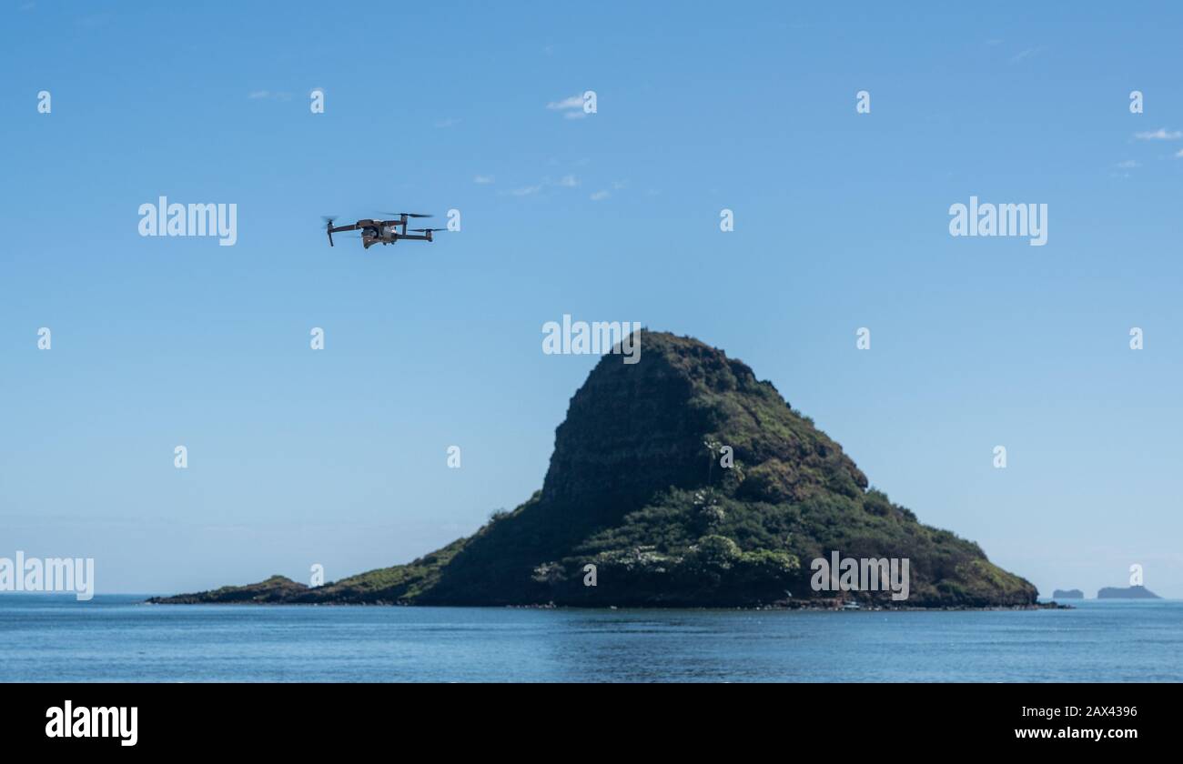 Drone moderne volant dans l'air devant le rocher de Chinaman ou Mokoli'i au large de la côte d'Oahu, Hawaï Banque D'Images