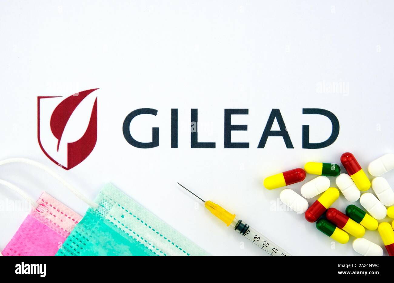 Logo de la société Gilead Sciences avec masques viraux, seringue et pilules. Photo à plat. Banque D'Images