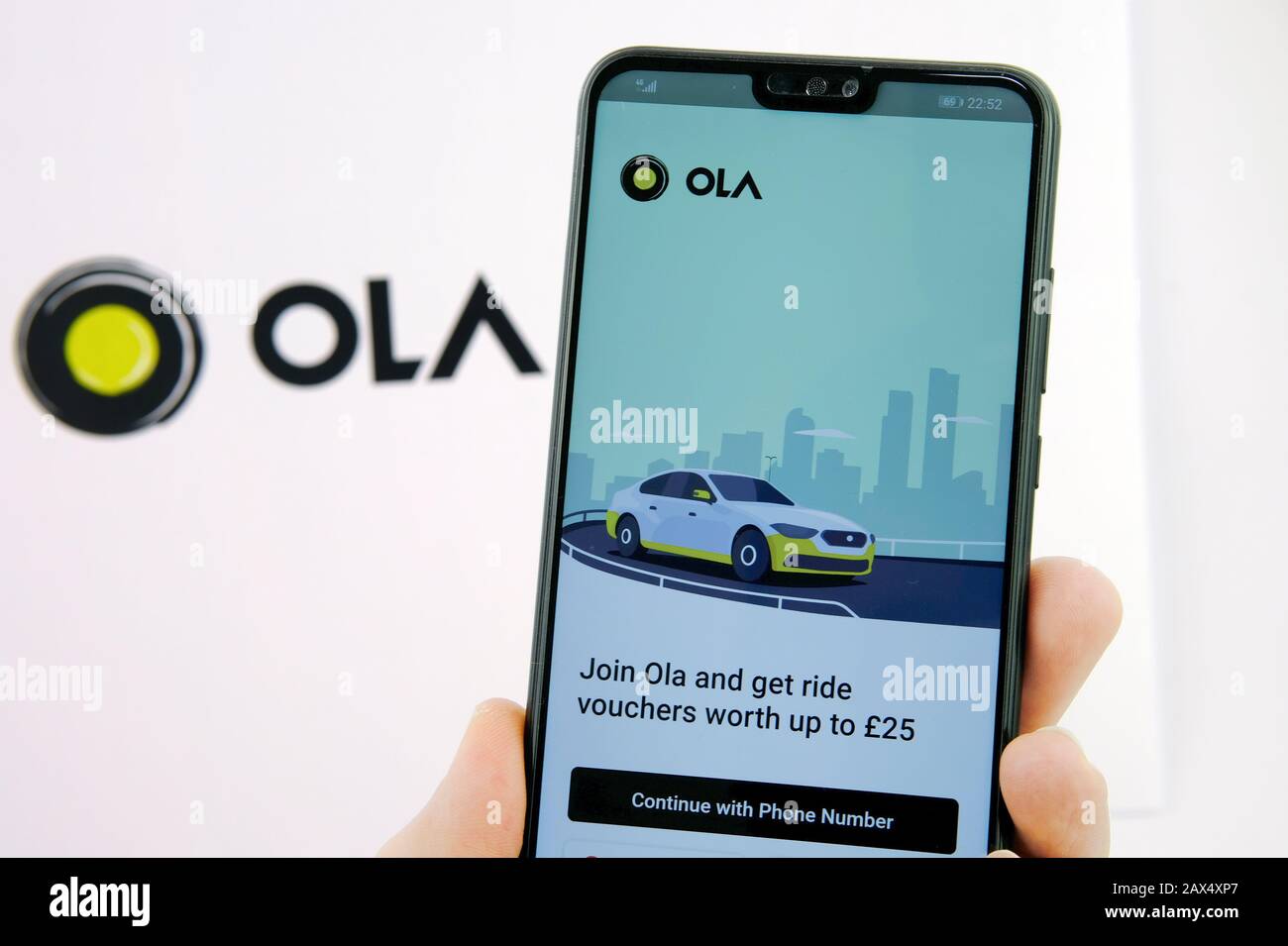 L'écran de connexion de l'application Ola Cabs sur le smartphone et le logo de l'entreprise sur un arrière-plan flou. OLA Cabs est une société de partage de parcours. Banque D'Images