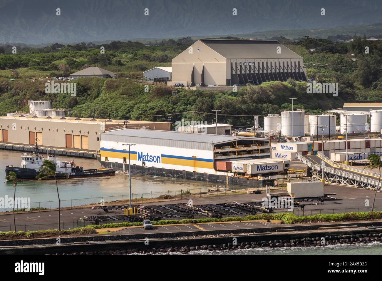 Nawiliwili, Kauai, Hawaï, États-Unis. - 17 janvier 2020: Matson a couvert la barge de conteneur d'expédition avec le remorqueur de puilling. Gardien Self Storage werehouse on Banque D'Images