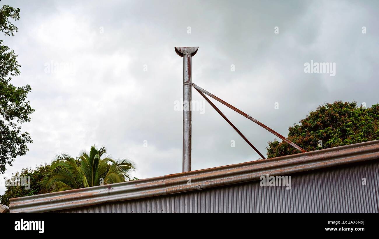 Une vieille fumée de fumée sur un toit en fer ondulé rouillé, isolée contre un ciel nuageux Banque D'Images