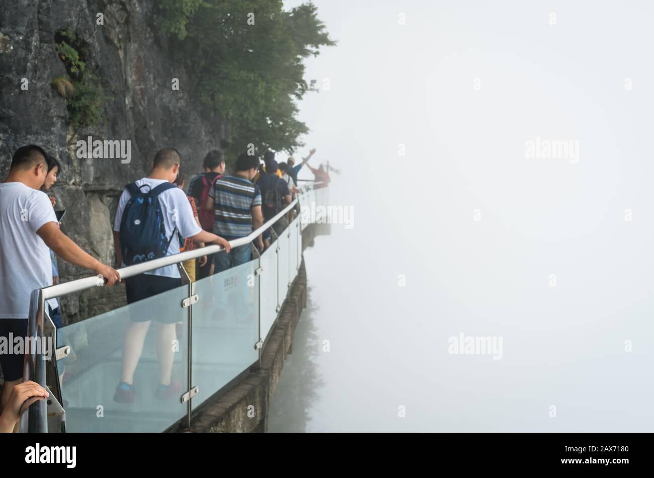 Zhangjiajie, Chine - Août 2019 : Les Touristes marchant sur une allée étroite en verre dans le parc naturel de Tianmenshan Banque D'Images