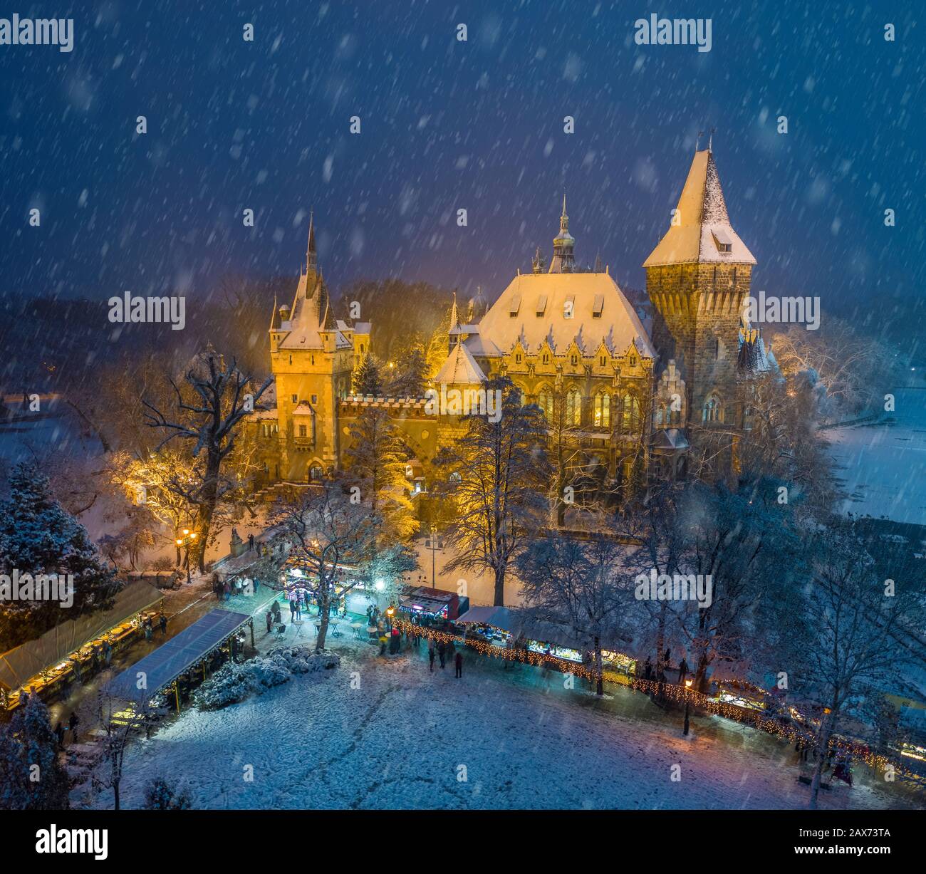 Budapest, Hongrie - marché de Noël dans le parc de la ville enneigée (Varosliget) d'en haut la nuit avec des arbres enneigés et le château de Vajdahunyad Banque D'Images