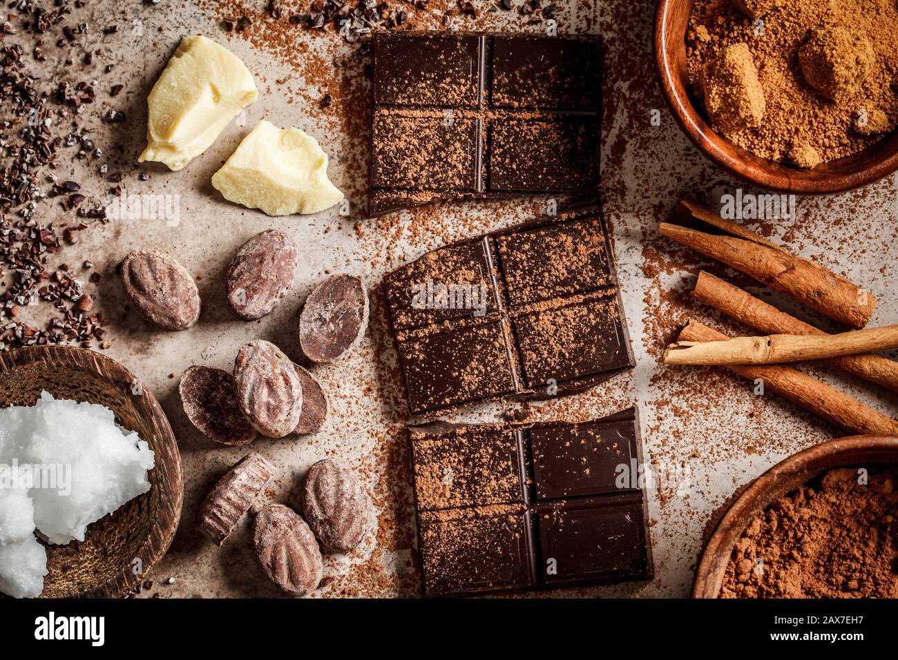 Ingrédients pour la fabrication de fond de chocolat. Cacao, beurre de cacao, sucre, cannelle et huile de coco sur fond sombre. Concept de chocolat. Banque D'Images