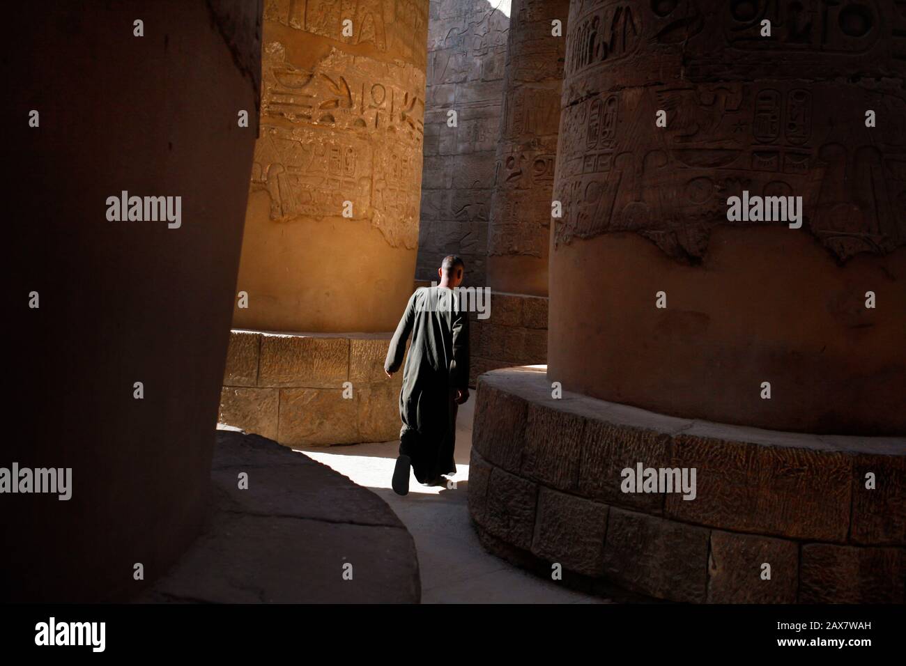 Louxor, Egypte, un homme traverse des piliers. Banque D'Images