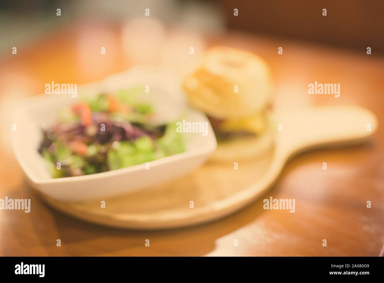Coup de flou artistique flou de cheeseburger et salade servi sur table en bois Banque D'Images