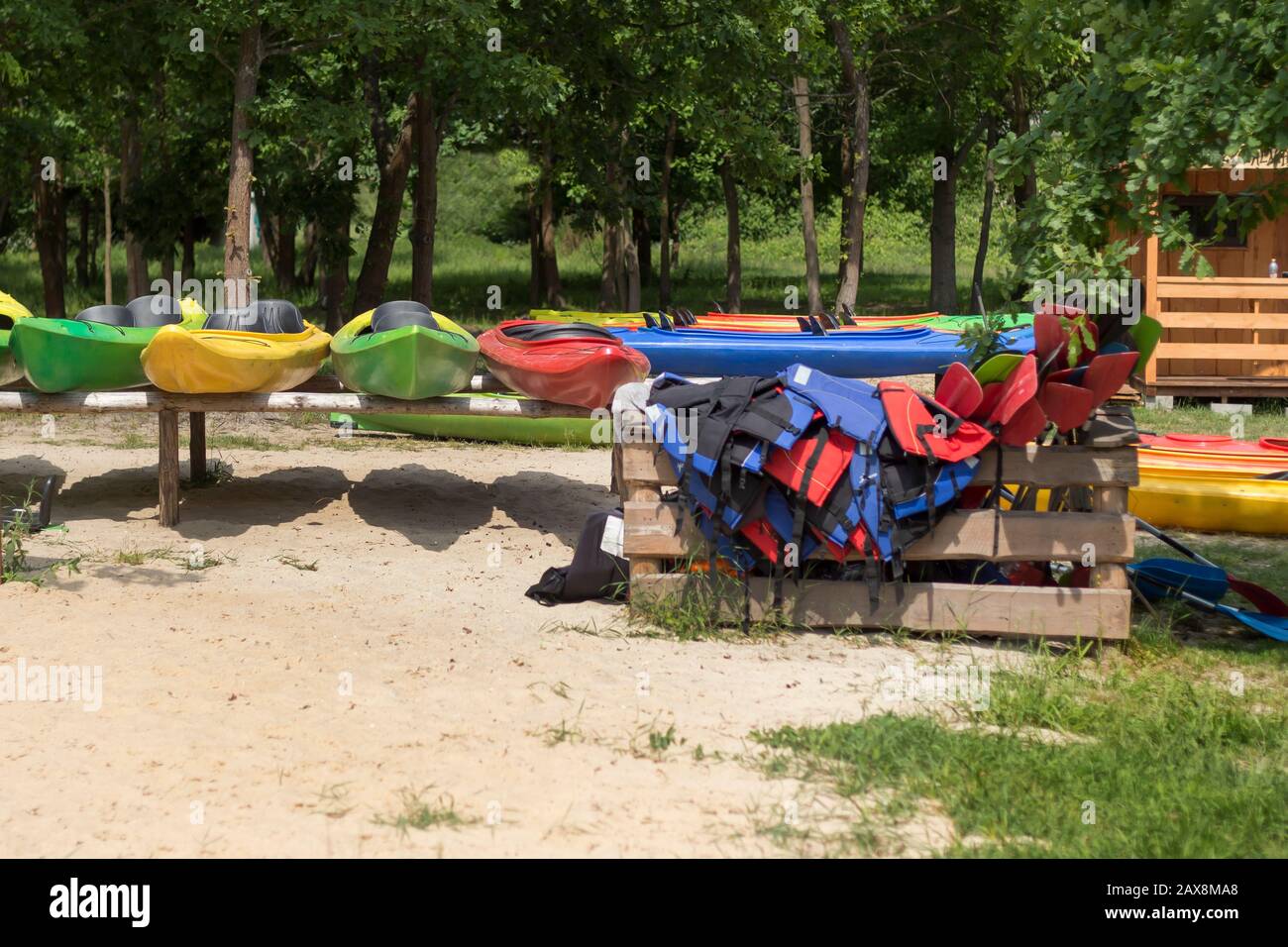 Location de kayak. Des kayaks de couleur placés sur des casiers sont sur la plage. Kapok et palettes disposés dans un récipient en bois. Banque D'Images