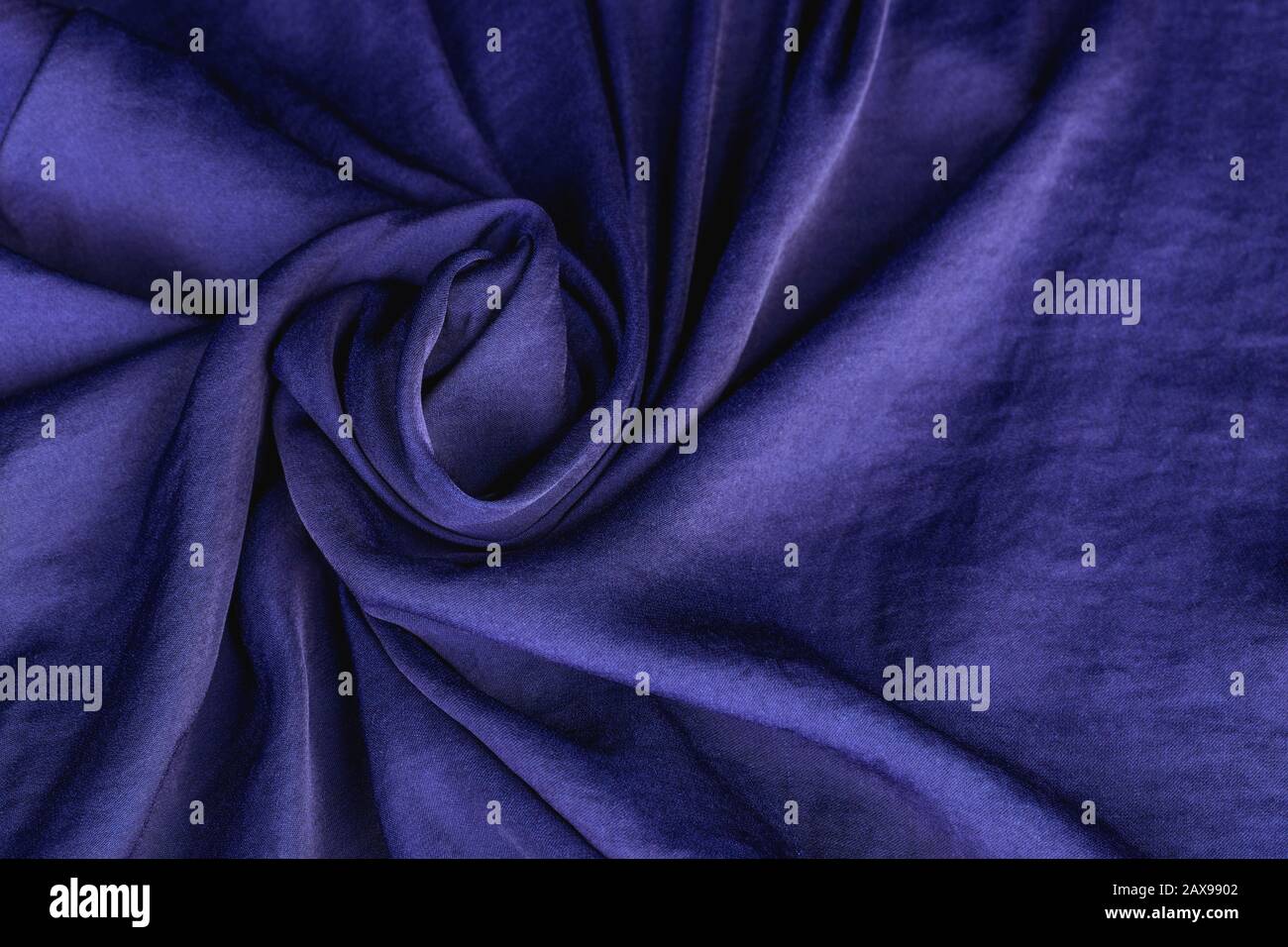 Texture, arrière-plan, motif. Tissu soie satin couleur cobalt, bleu roi classique. Drapez le matériau en forme de fleur. Banque D'Images