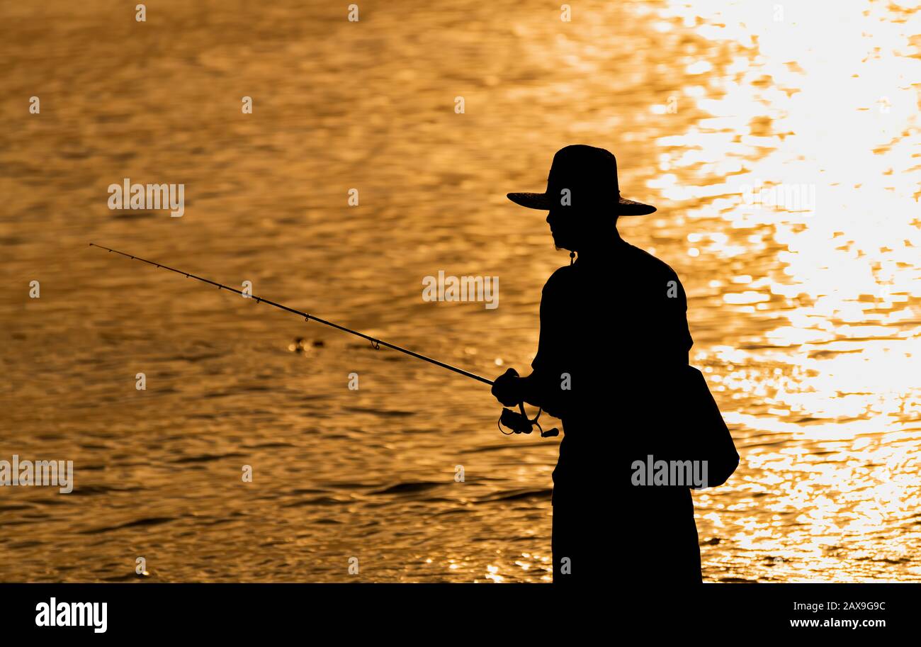 Silhouette d'homme de pêche avec lumière chaude et coucher de soleil basse sombre vue ombre. Banque D'Images