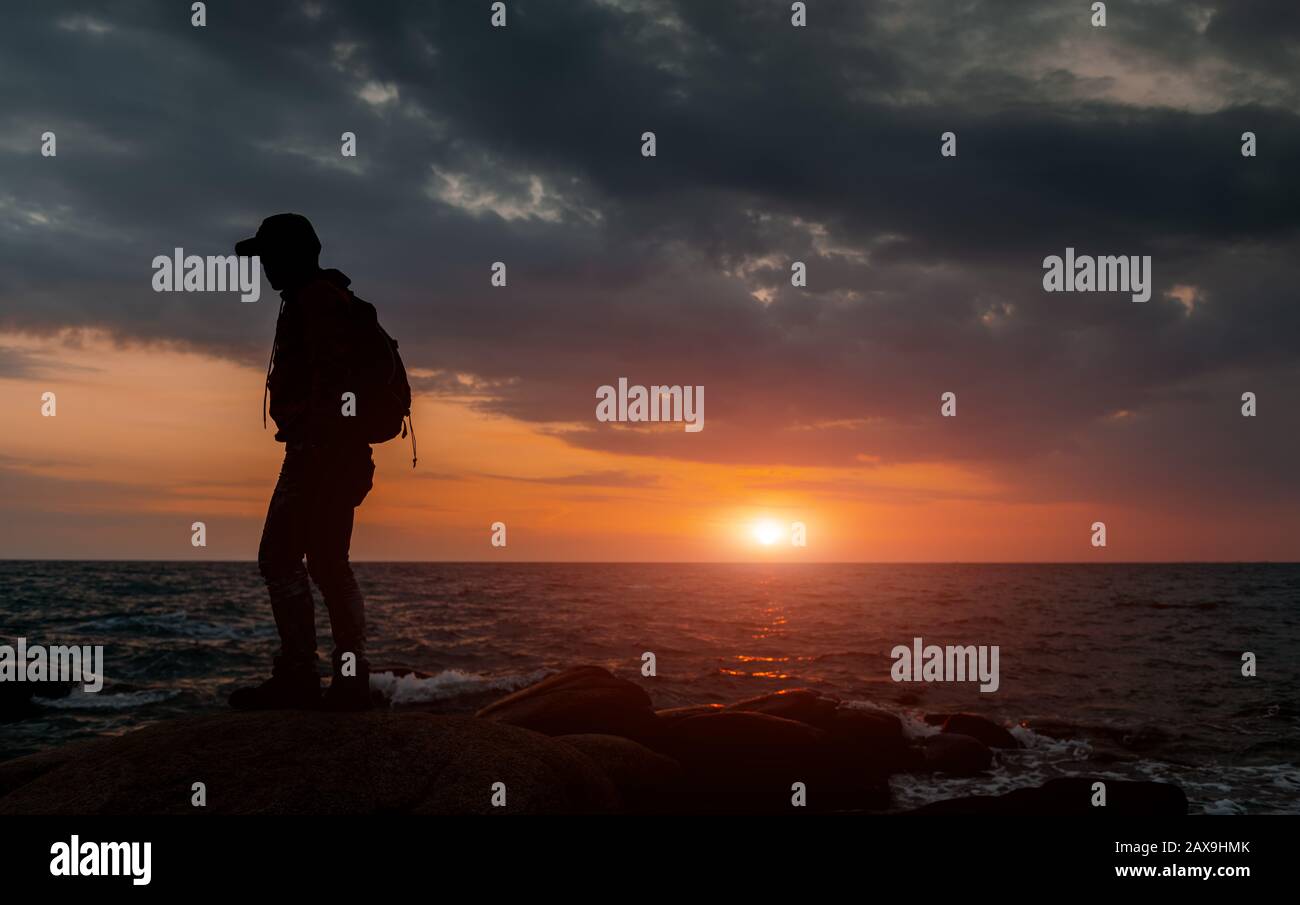 Silhouette de routard avec vue à l'ombre sombre et au coucher du soleil. Banque D'Images