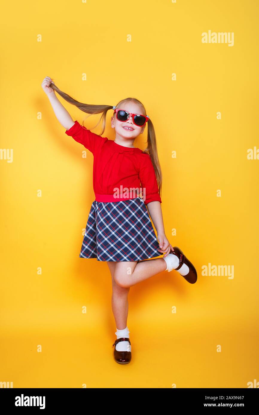 Petite fille tendance en vêtements d'été et lunettes de soleil dansant sur  fond jaune Photo Stock - Alamy