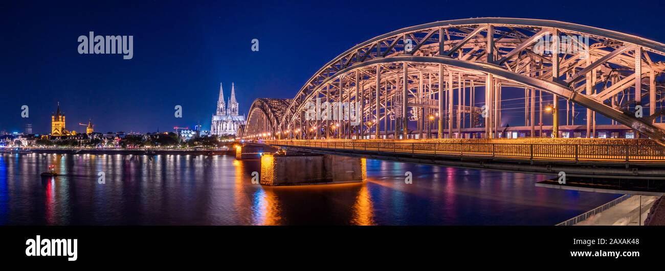 Panorama nocturne du pont lumineux Hohenzollern sur le Rhin. Magnifique paysage urbain de Cologne, Allemagne avec cathédrale et Grand Saint-Martin C Banque D'Images