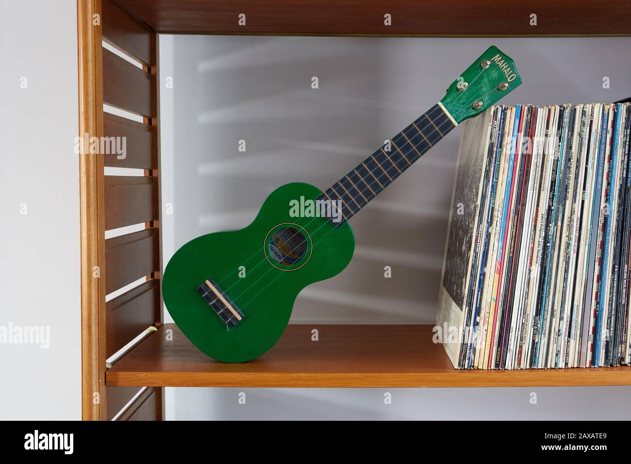 Une collection d'albums sur une étagère avec un vert Mahaloo Ukulele. Banque D'Images