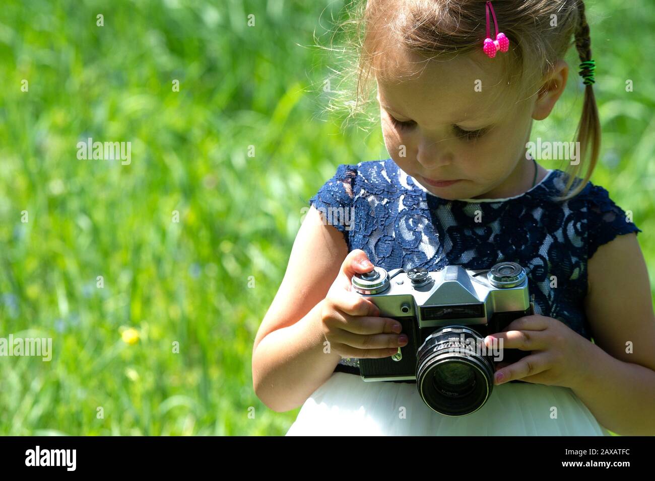 Une petite fille prend une photo avec un appareil photo rétro de film en été dans le parc. Petite jolie fille enfant en robe légère tenant rétro vintage p Banque D'Images