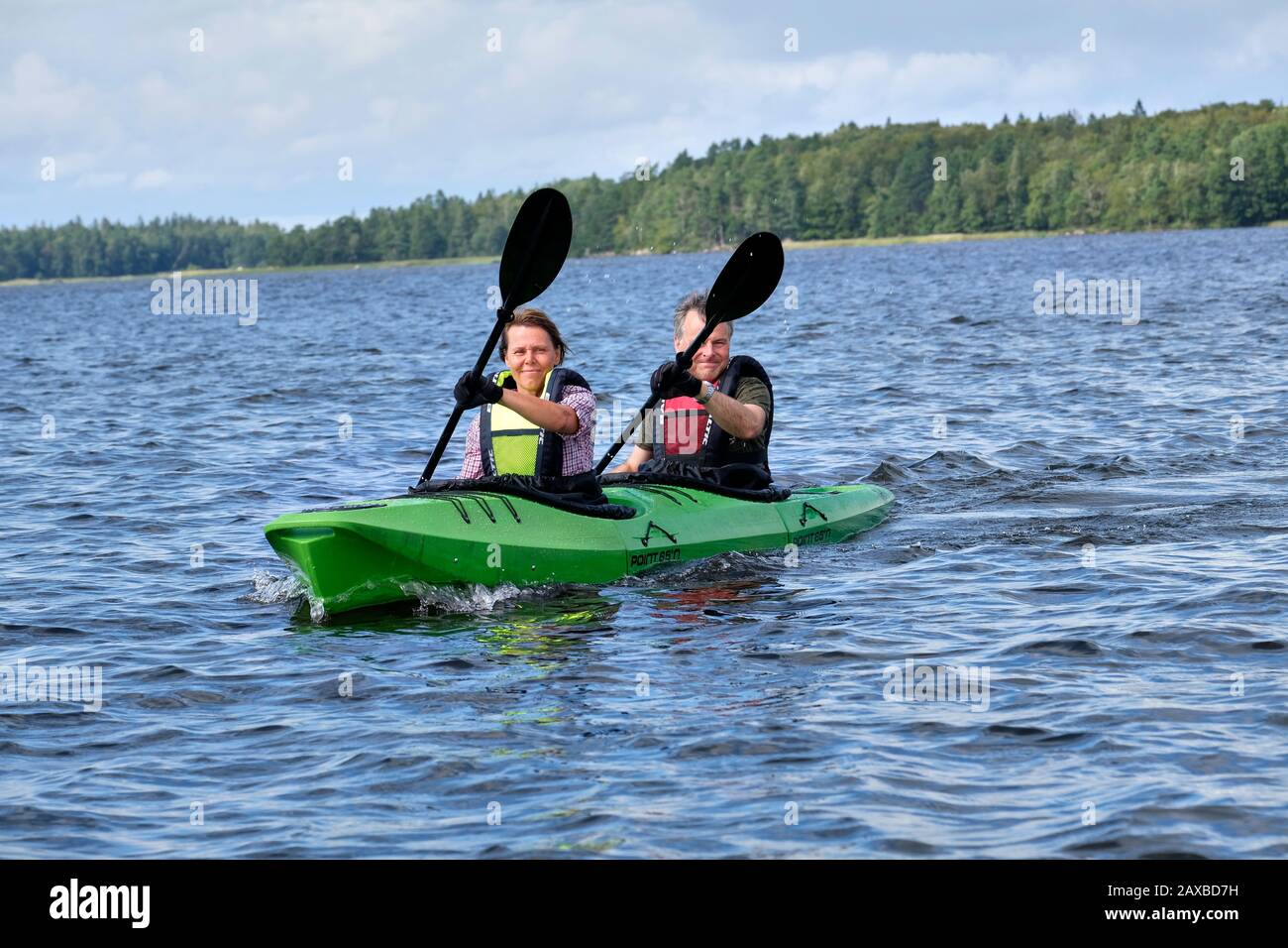 Couple masculin et féminin kayak à l'unisson sur le lac Åsnen, Suède Banque D'Images