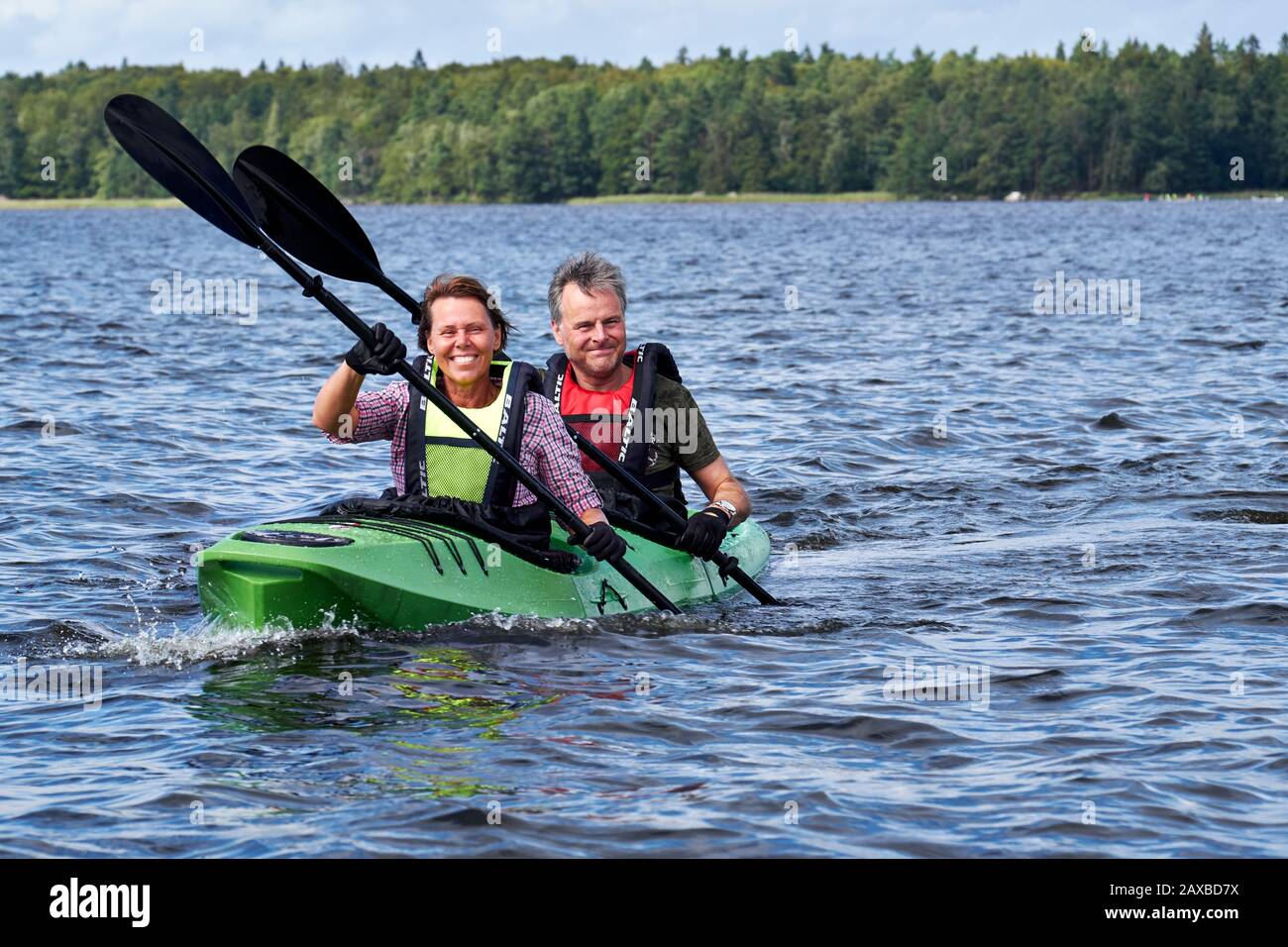 Couple masculin et féminin kayak à l'unisson sur le lac Åsnen, Suède Banque D'Images