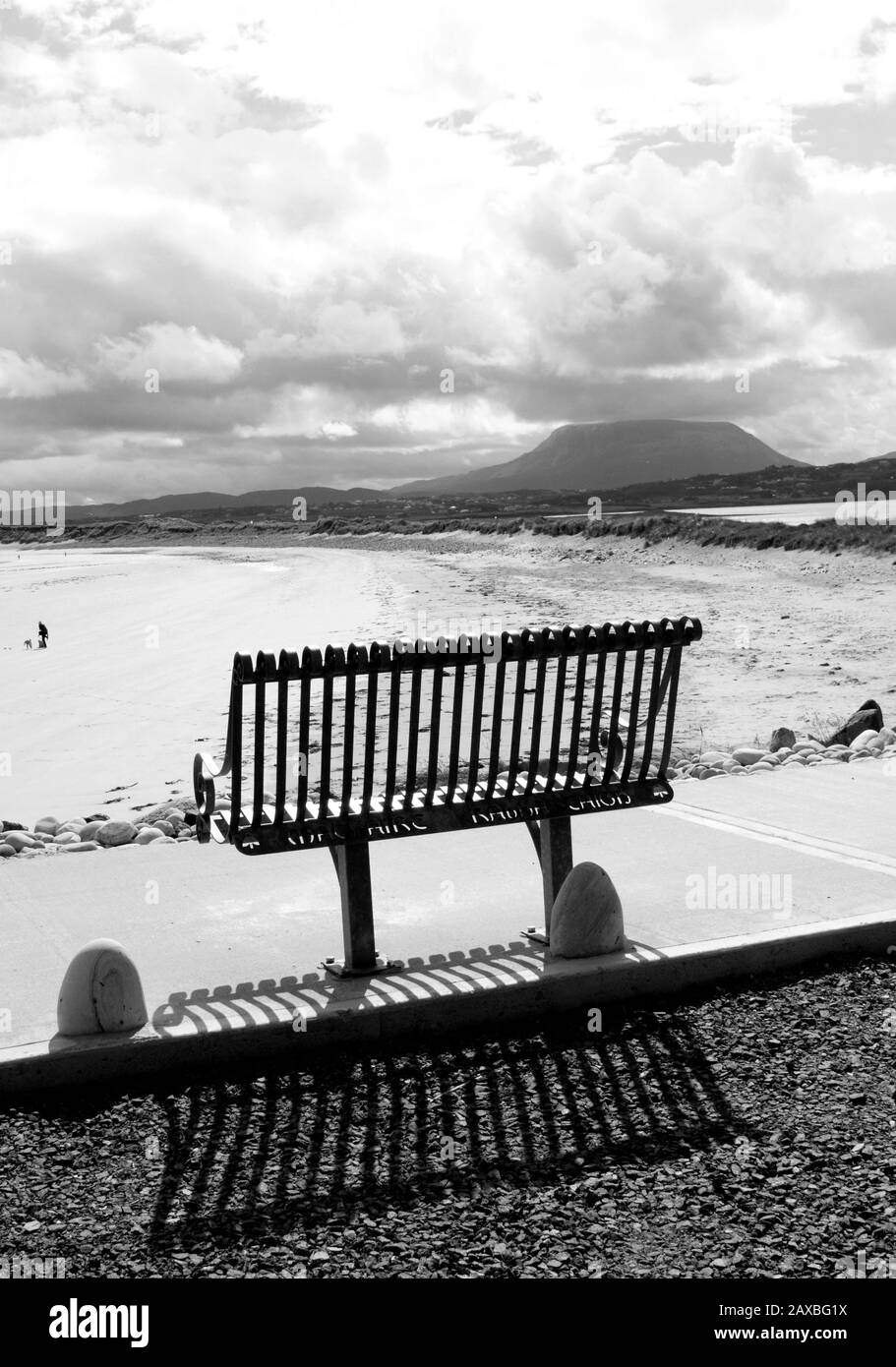 Un banc en métal jette une ombre avec une plage isolée et une montagne en arrière-plan. Magheraroarty, Co. Donegal, Irlande Banque D'Images