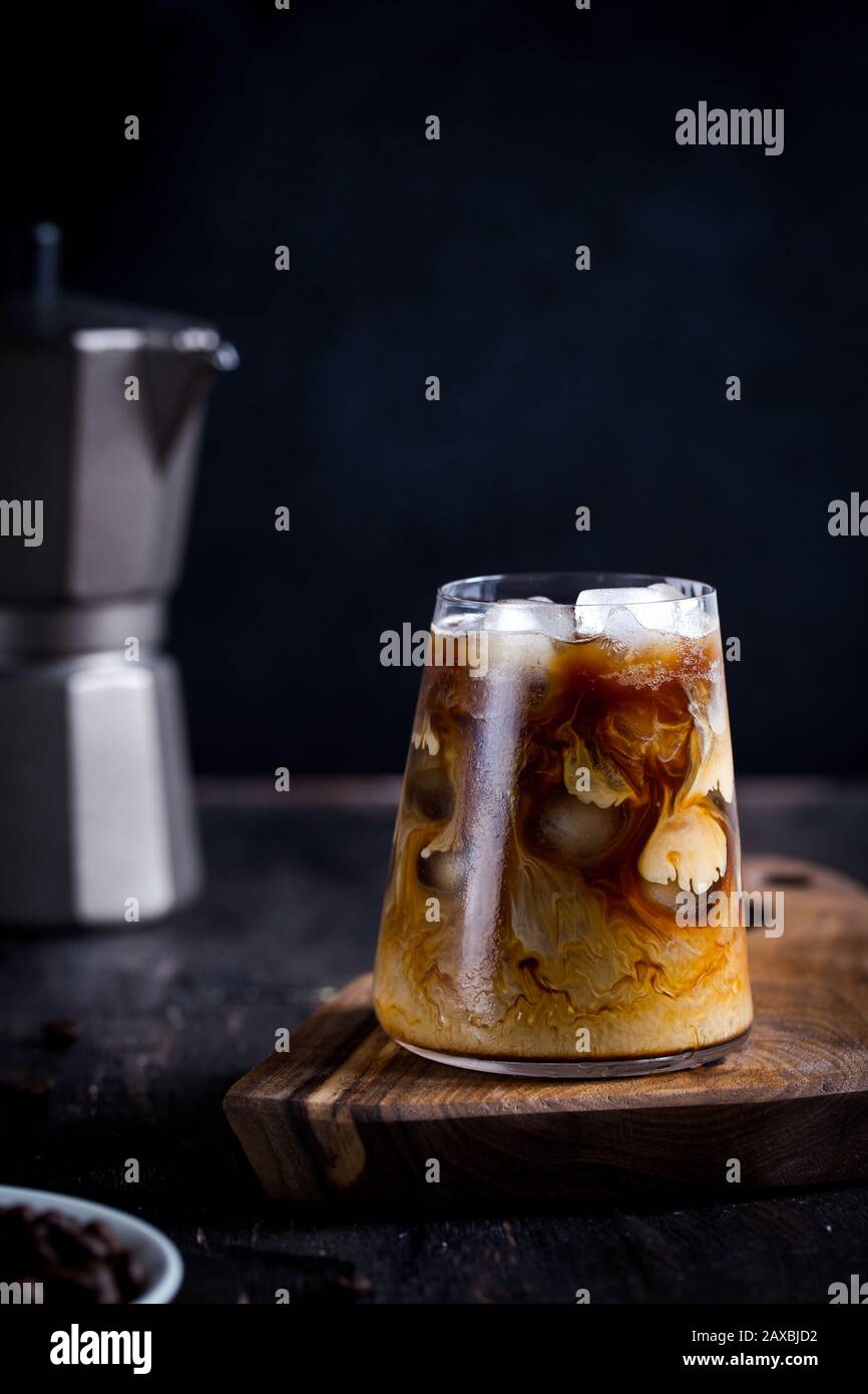 boisson froide et tardive avec glace. Café glacé sur une table en bois avec de la crème versée dans elle montrant la texture/ Banque D'Images