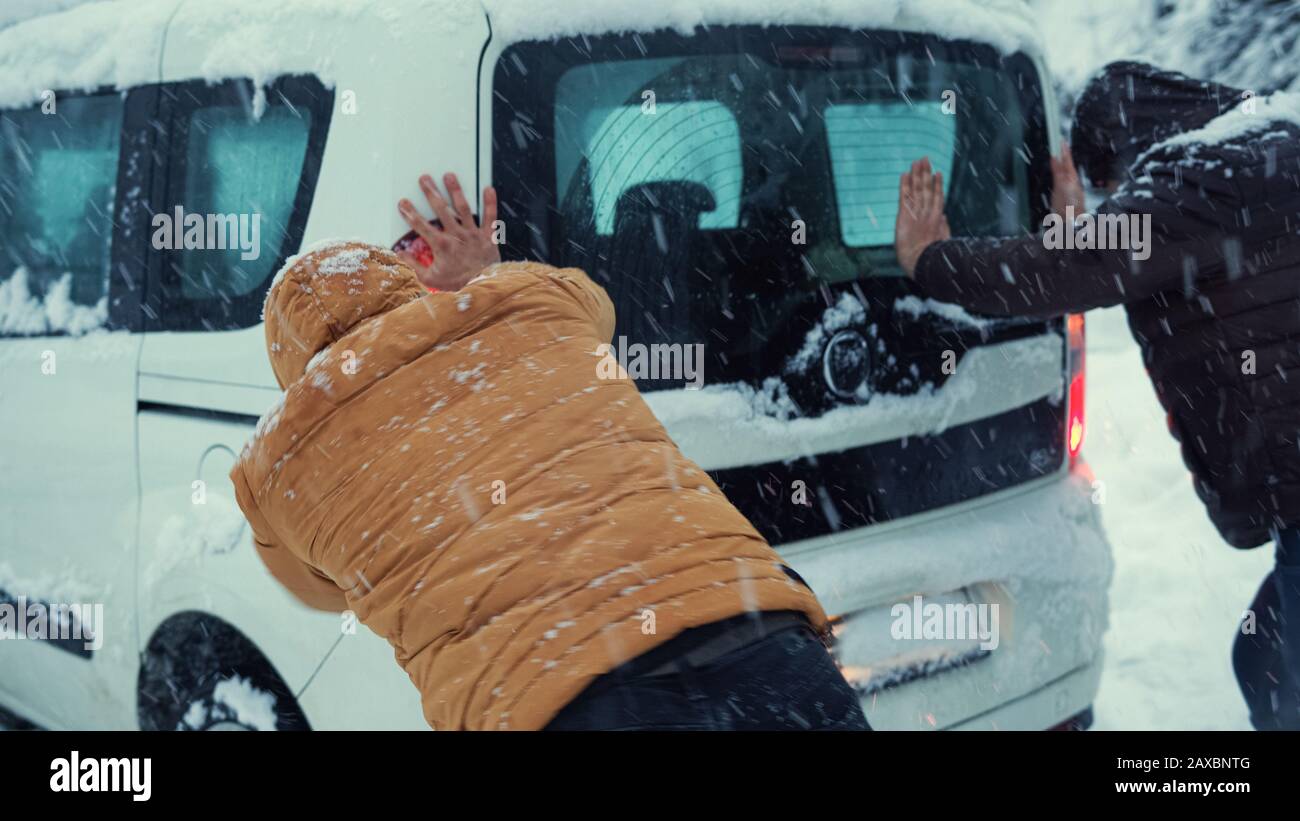 Voiture coincée dans la neige sur la route, les gens essaient de la retirer.concept de transport. Banque D'Images
