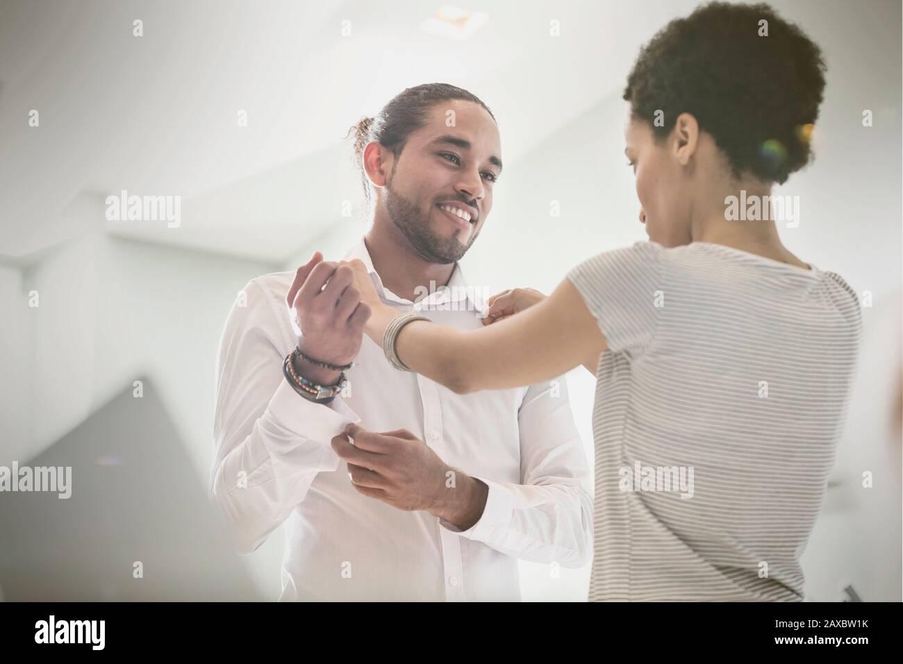 Femme aidant petit ami à s'habiller, ajuster le col de chemise Banque D'Images