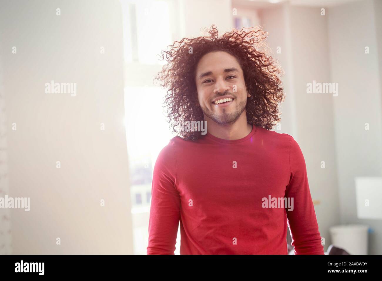 Portrait confiant, sourire jeune homme avec des cheveux frisés Banque D'Images