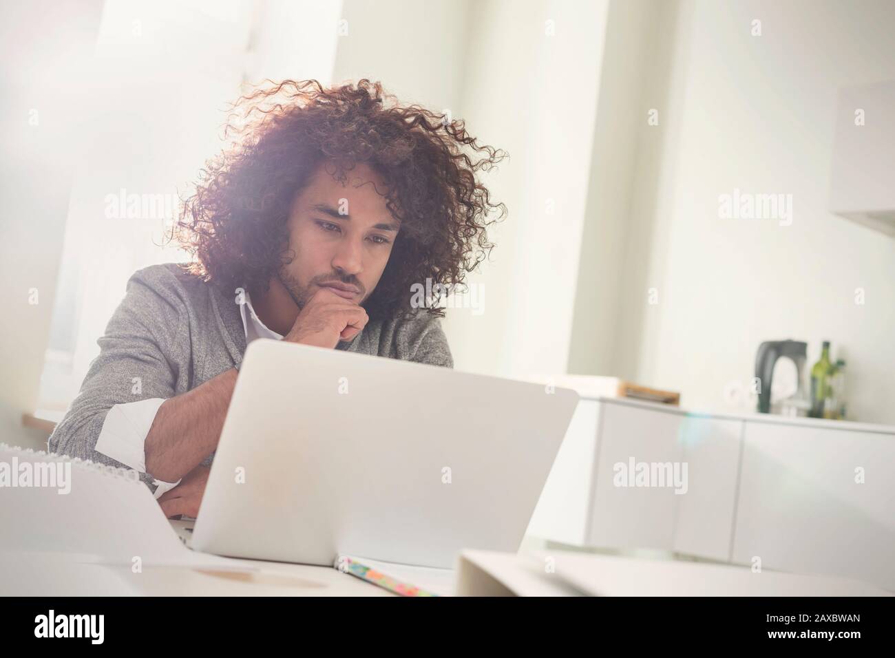 Un jeune homme concentré travaillant sur un ordinateur portable Banque D'Images