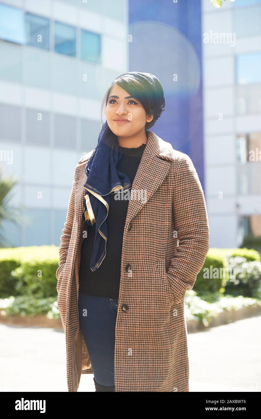 Portrait heureuse jeune femme en foulard regardant dans le parc ensoleillé Banque D'Images