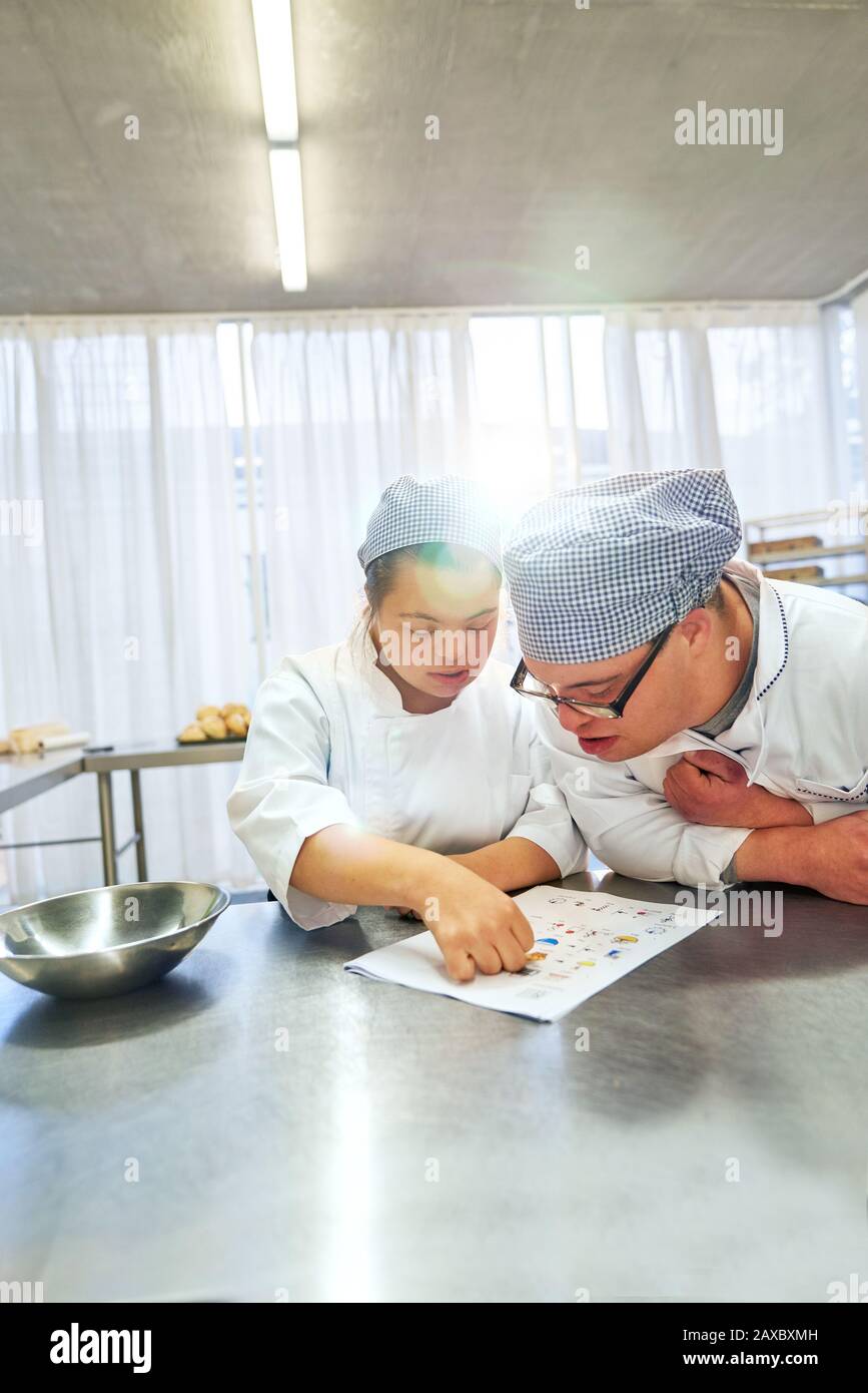 Jeunes étudiants avec syndrome De Down regardant la recette dans la cuisine Banque D'Images