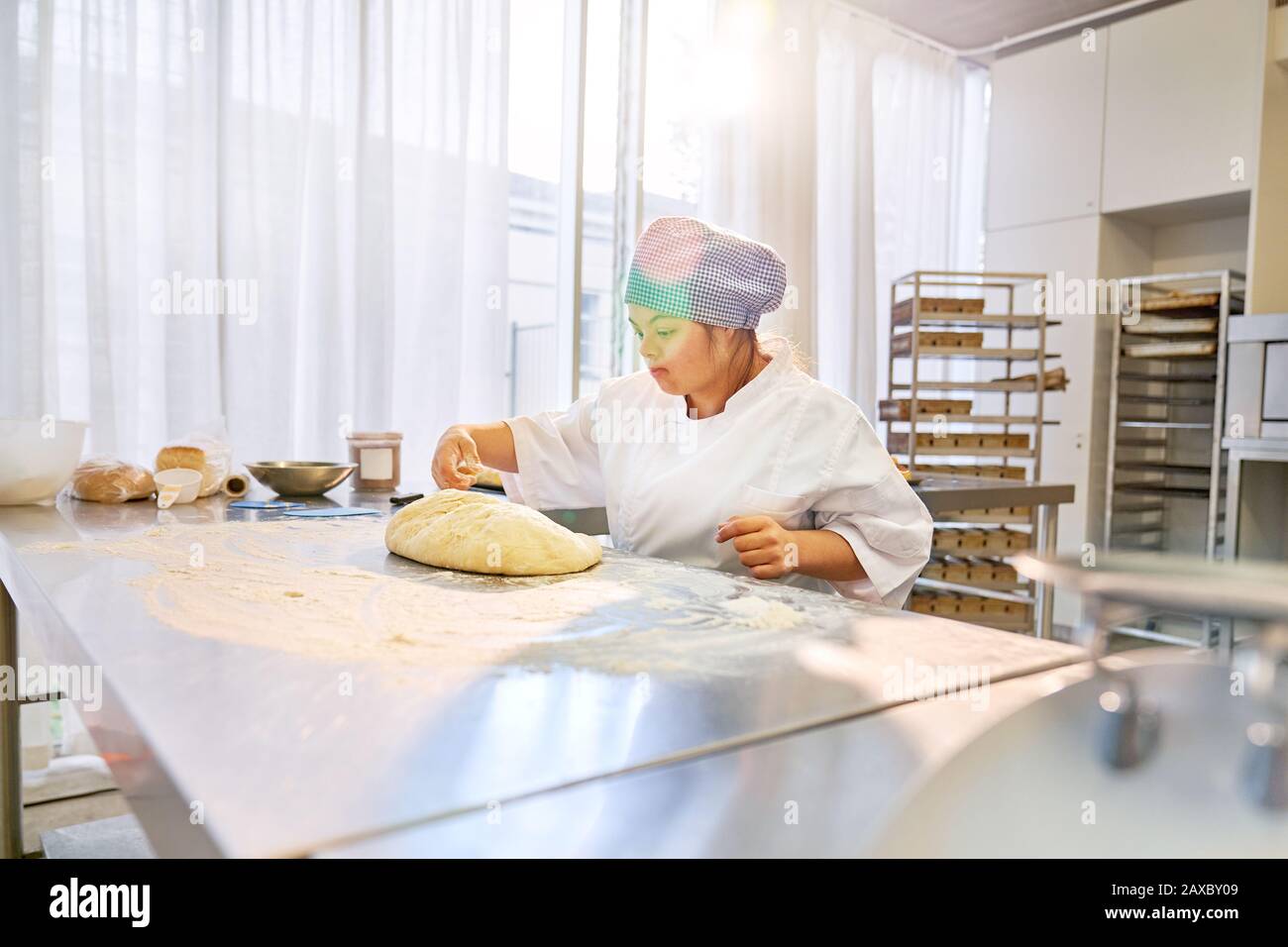 Jeune femme avec syndrome De Down préparer de la pâte à pain dans la cuisine Banque D'Images