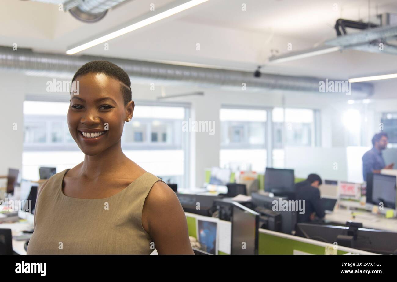 Portrait souriant, femme d'affaires confiante dans un bureau en plan ouvert Banque D'Images