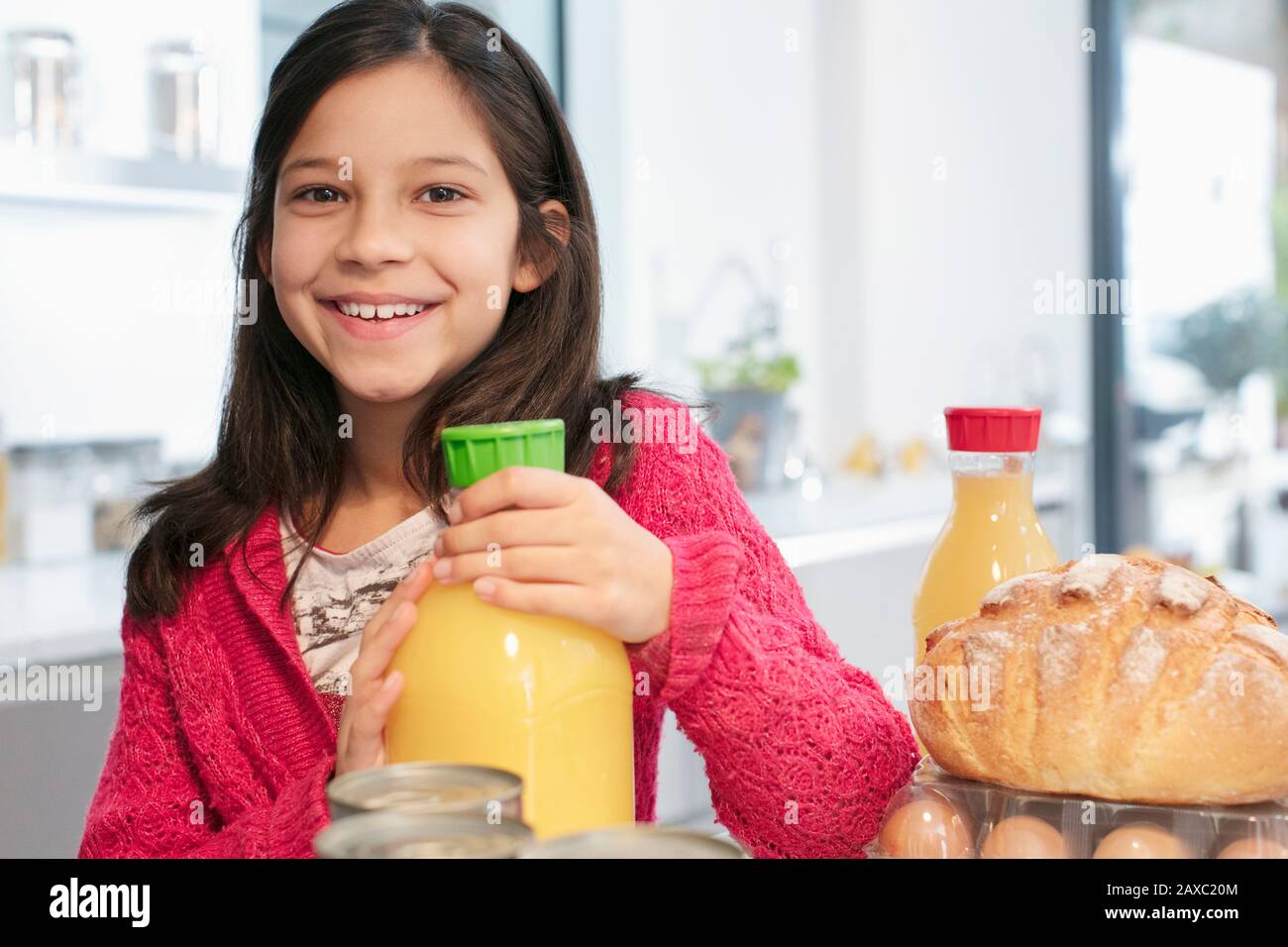 Portrait fille souriante avec jus d'orange dans la cuisine Banque D'Images