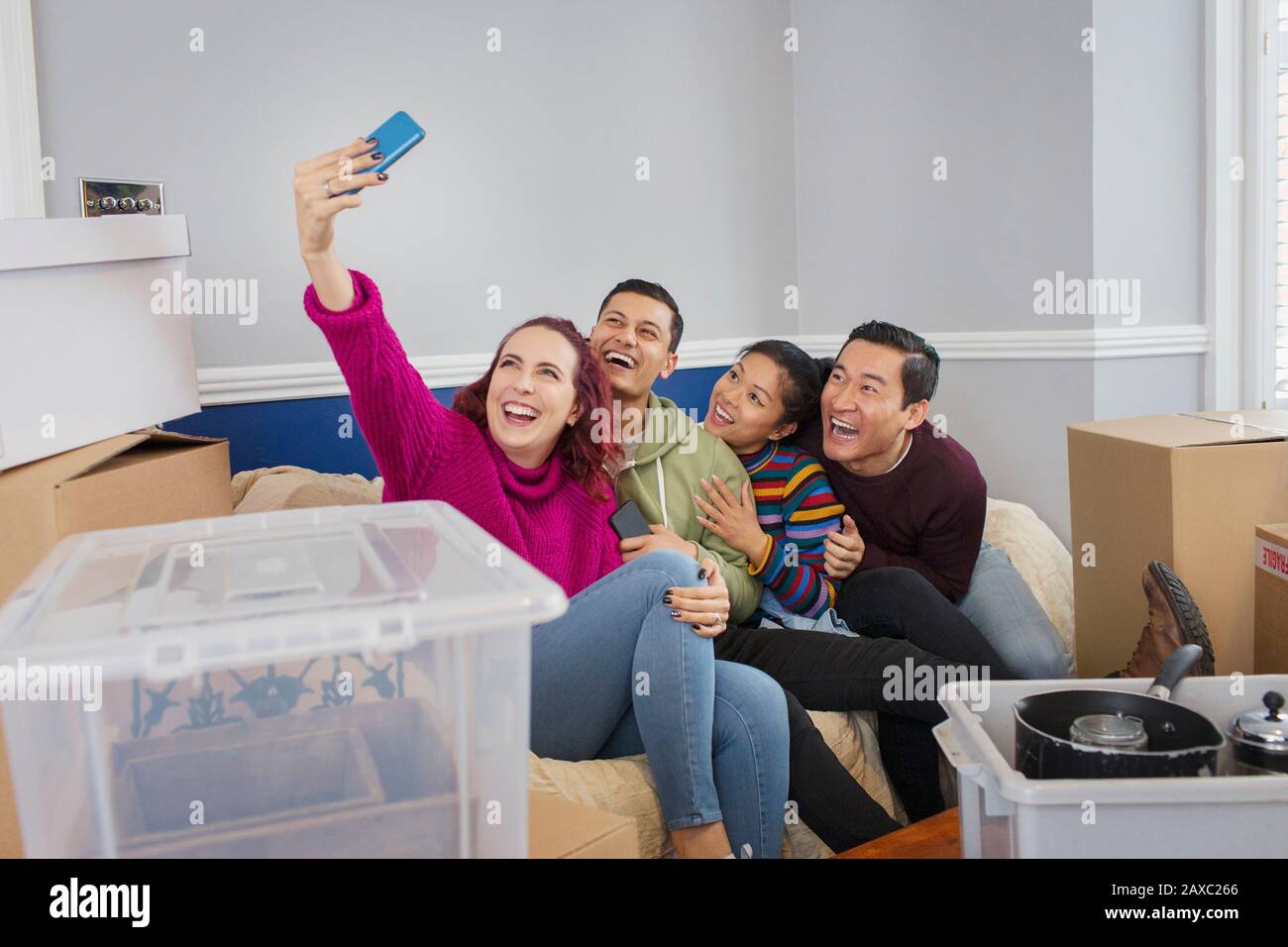 Joyeux amis qui prennent une pause pour se déplacer, prendre selfie sur le canapé Banque D'Images