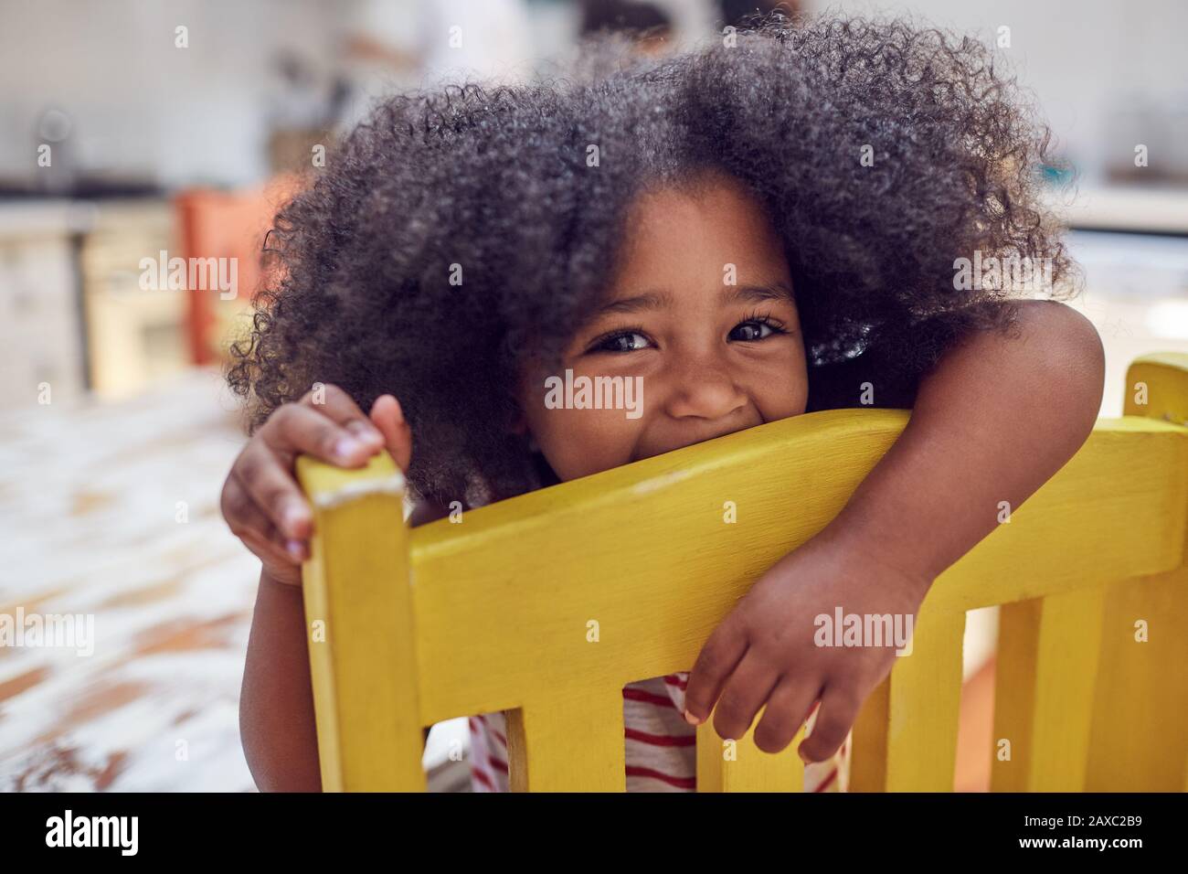 Portrait fille mignonne sur chaise jaune Banque D'Images