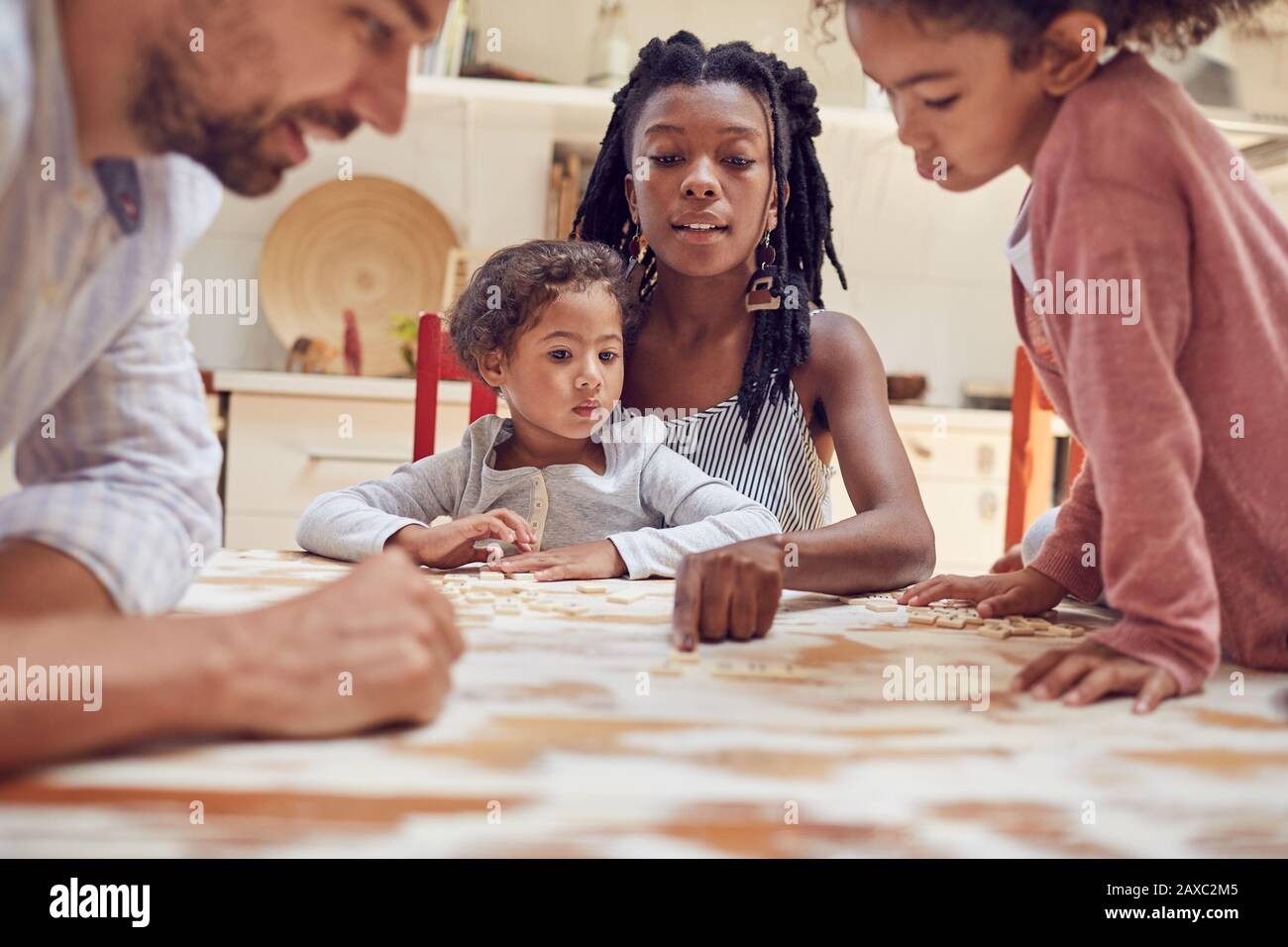 Jeune famille jouant au jeu de mots à la casse à la table Banque D'Images