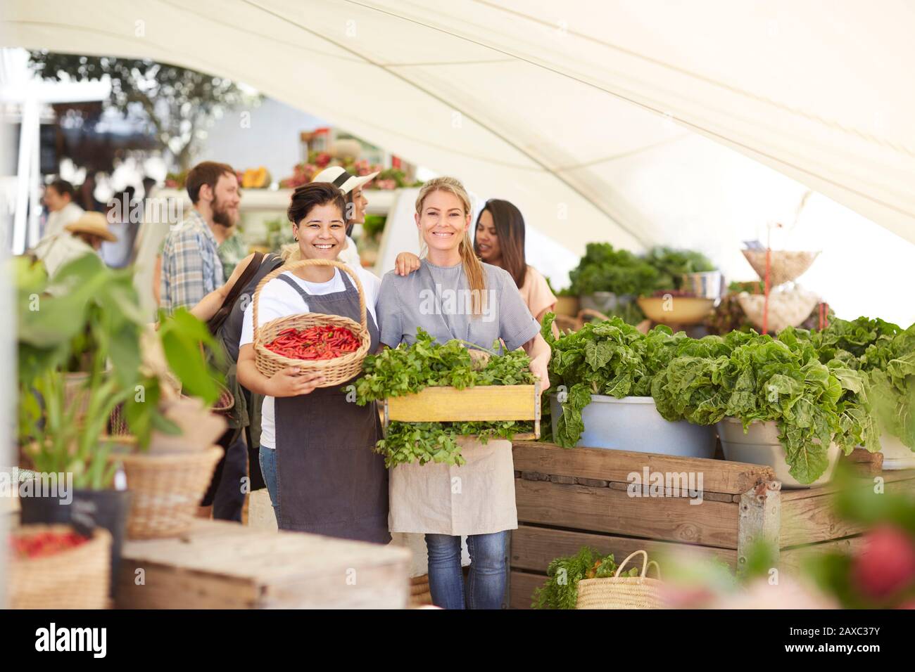 Portrait souriant des travailleuses avec des légumes sur le marché des agriculteurs Banque D'Images