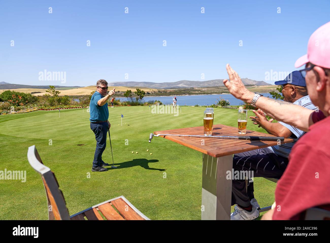 Des amis golfeurs masculins boivent de la bière et pratiquent la mise Banque D'Images