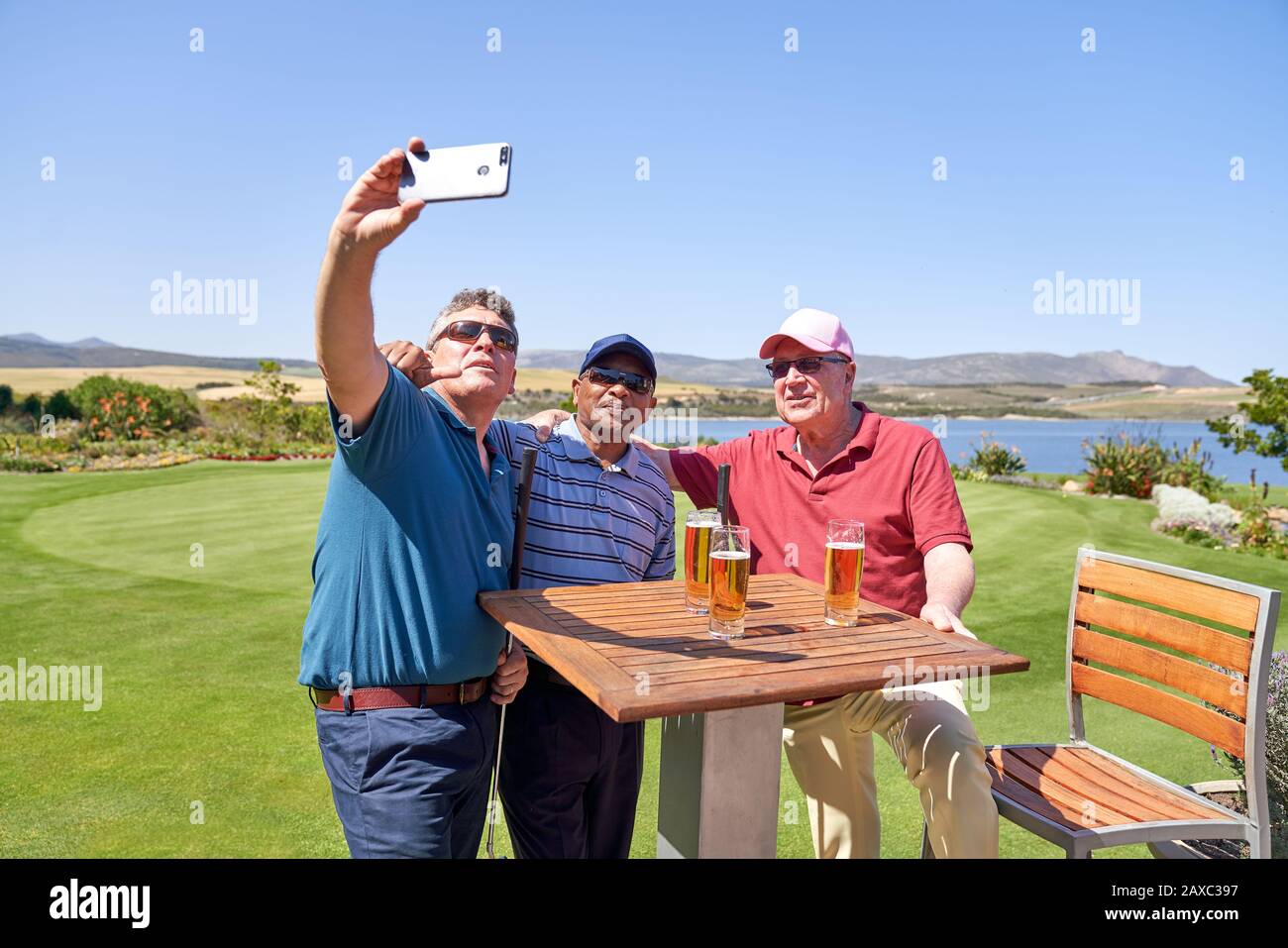 Des amis masculins boivent de la bière et prennent le selfie sur le patio du parcours de golf Banque D'Images