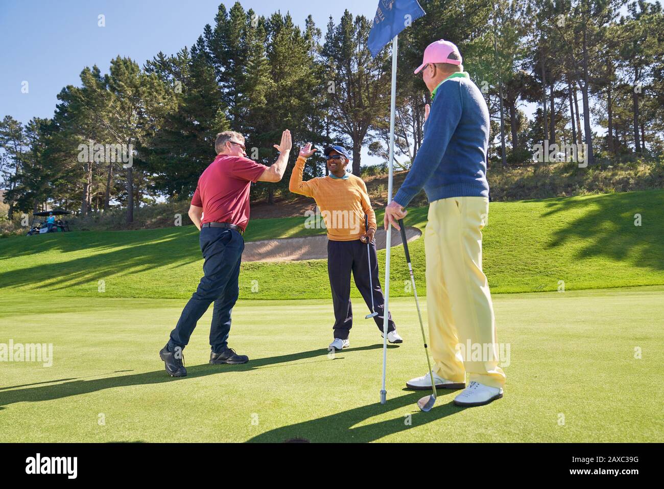 Les amis hommes haut fiving sur le terrain de golf ensoleillé vert d'exercice Banque D'Images